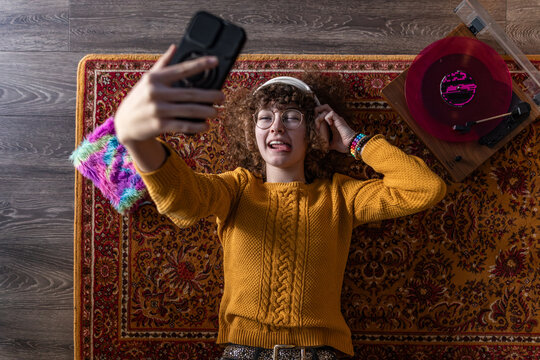 Music fan taking a playful selfie with a smartphone indoors