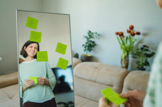 Woman smiling at positive affirmations on a living room mirror