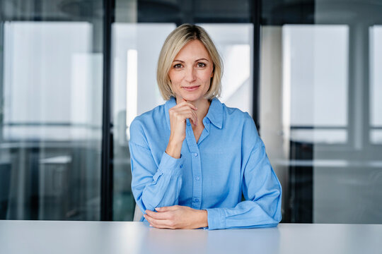 Woman in a modern office setting smiling confidently at the camera