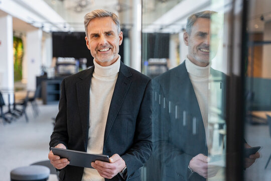 Smiling businessman with tablet in modern office