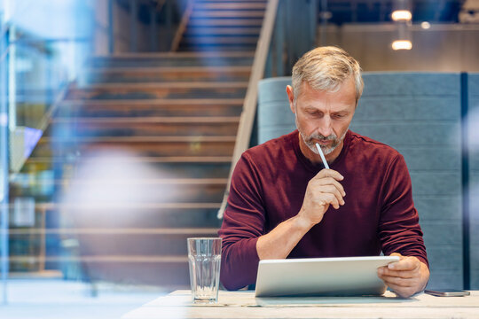 Man thinking while working with tablet in modern office setting