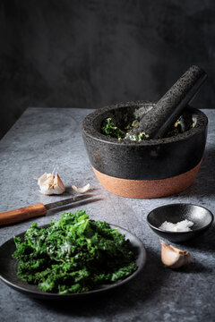 Preparing homemade vegan kale pesto with mortar and pestle
