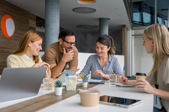Business team collaborating in modern office with laptop and documents