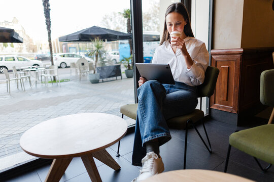 Freelancer working on laptop and drinking coffee in a cafe