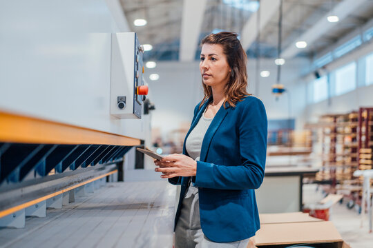 Businesswoman with tablet PC examining machinery at workshop