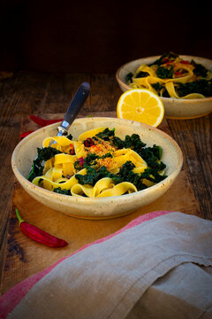 Rustic tagliatelle pasta with kale and chili crunch on a wood table