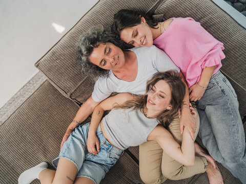 Mother cuddling with daughters on couch showing family affection