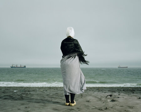Figure in traditional Dutch costume looking at sea in Zeeland