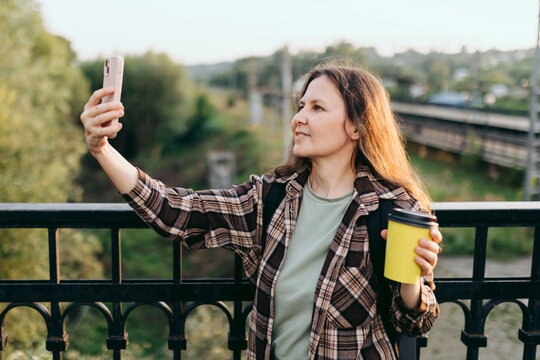 Commuter taking selfie with coffee at railway station