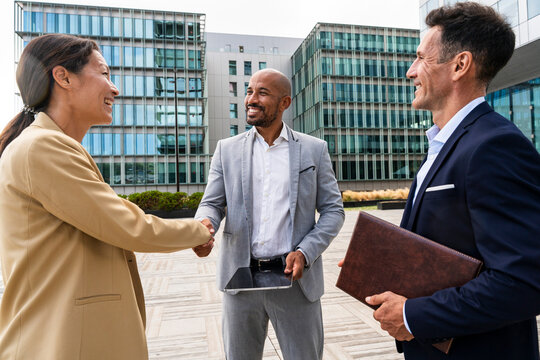 Smiling coworkers shaking hands outdoors in the city