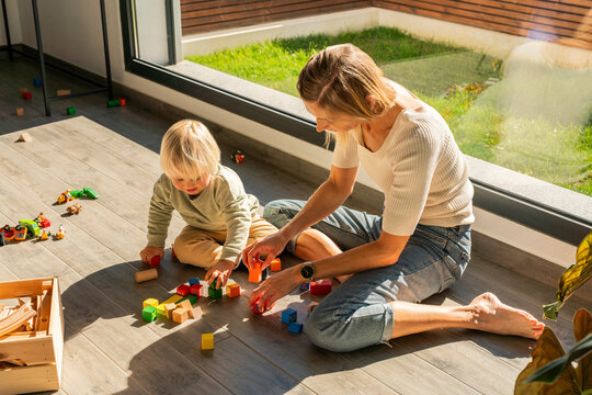 Mother and son spending leisure time playing with building blocks at home