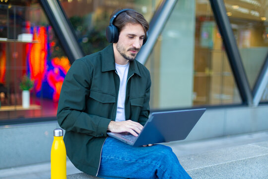 Digital nomad working remotely on laptop with headphones outdoors