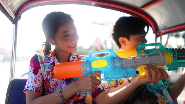 Young Asian Couple Celebrating Songkran Festival with Water Guns in Tuk Tuk