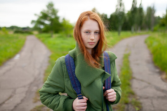 Hiker with red hair and backpack at a crossroad in summer