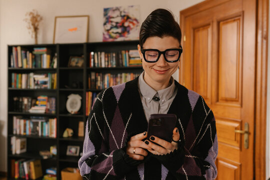 Creative director smiling and texting on smartphone indoors