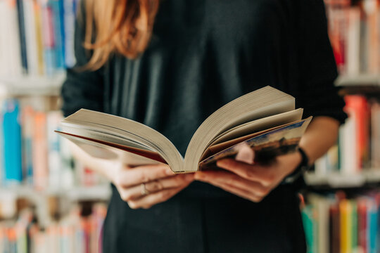 Unrecognizable person holding an open book in a library