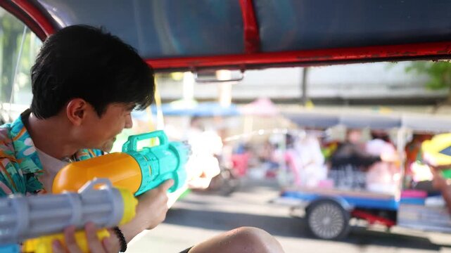 Asian Man Shooting Water Gun from Tuk Tuk During Songkran Festival