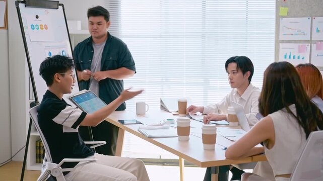 Young Asian colleagues teamwork in modern office space Discussing market trends and conducting data analysis to develop a successful business strategy together