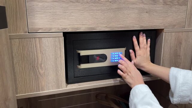 Woman in white terry robe closing digital code safe, hotel room security, beeping lock, private storage.