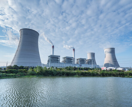 Large-Scale Coal-Fired Power Plant with Cooling Towers Near Pond Under Cloudy Sky