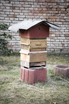 A Rustic Wooden Beehive Stacked Neatly Against an Old Red Brick Garden Wall