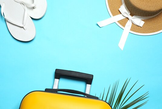 Composition with suitcase, flip-flops and sunhat on bright blue background. Summer travel concept, top view