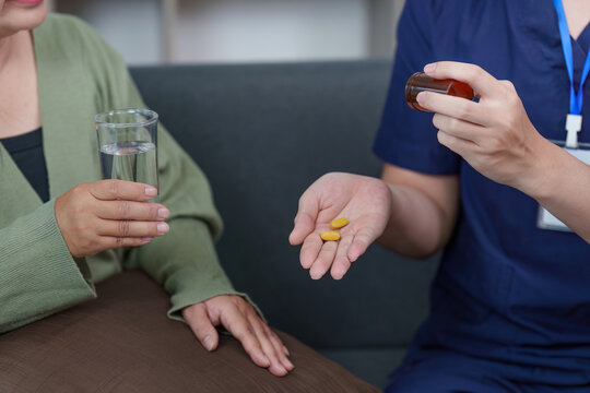 Asian healthcare professional giving medication to woman patient