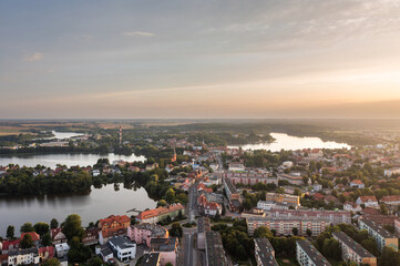 Obraz premium Sunset aerial cityscape with rooftops, water and surrounding fields in Walcz, West Pomerania, Poland.