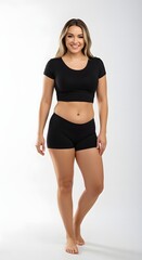 Fototapeta premium Full-body portrait of a confident woman in activewear showcasing her toned physique after successful breast augmentation, tummy tuck, and liposuction surgeries, isolated on a light background.