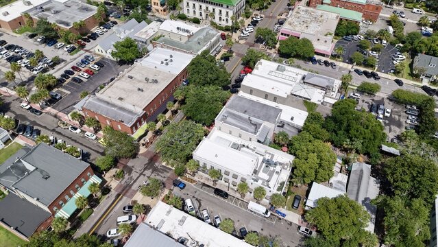 Aerial view of buildings with a mix of brick and white facades, interspersed with lush trees and parked cars, Fernandina Beach, Florida, United States.