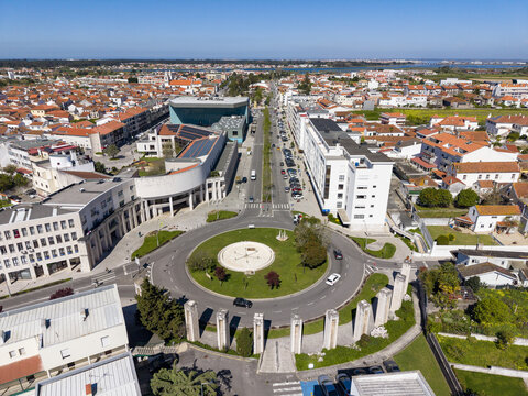 Aerial view of a vibrant roundabout with lush greenery and surrounding buildings under a clear blue sky, Aveiro, Portugal.
