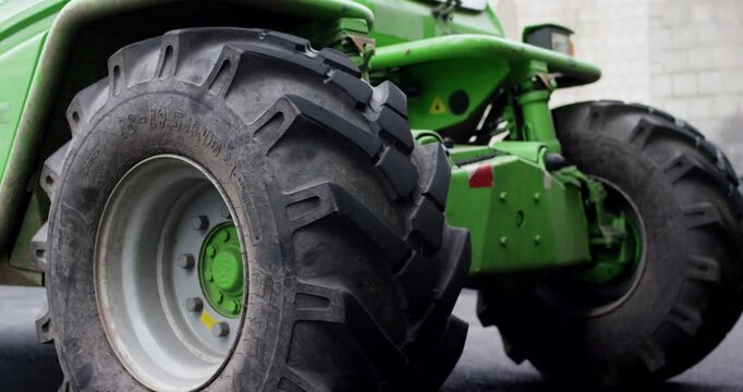 A green wheel loader picks up and dumps a pile of black recycled plastic granulate in a warehouse.