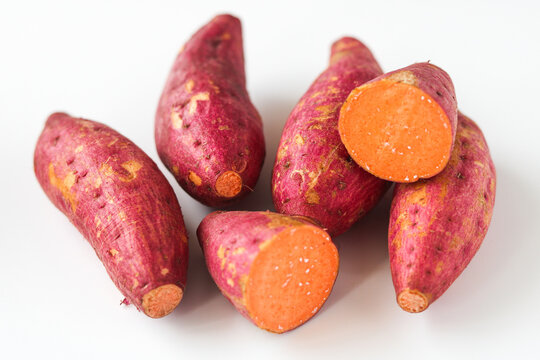 Closeup on a group of raw sweet potatoes, isolated on a clean white background.