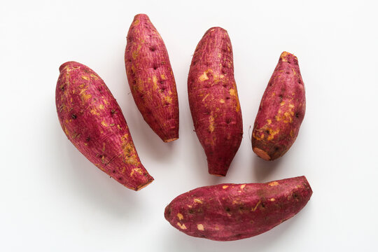 Top view of five raw sweet potatoes, isolated on a clean white background.
