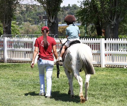 Caballo poni y ni&ntilde;o en paseo a caballo en h&iacute;pica ecuestre para aprender con monitora y moza de actividad al aire libre para cr&iacute;os peque&ntilde;os