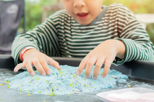 Close-up of children's hands playing with colored sand and buckets on the table