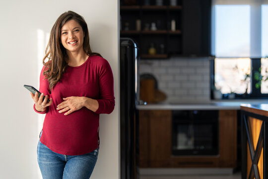Happy relaxed young pregnant woman using cell phone, smiling lady laughing holding smartphone