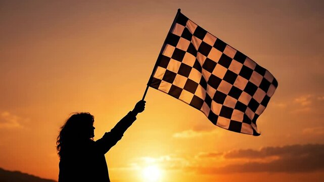 Silhouette of a person holding a checkered flag against a sunset sky.