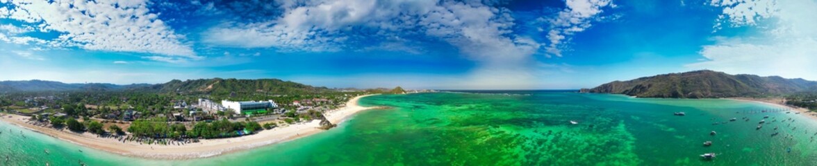 Fototapeta premium Stunning overhead panorama of Kuta Lombok coastline featuring tropical shoreline palm trees and crystal clear sea under blue sky