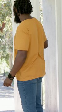 Vertical video: Man opening home door, welcoming daughter, hugging at door, phone and bag showing