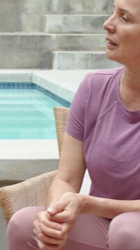 Vertical video: Turning woman replying to pointing hands at pool, with purple shirt, copy space