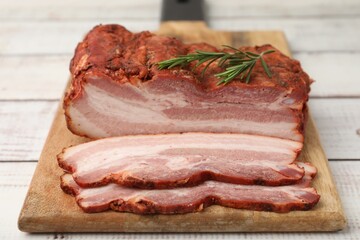 Fototapeta premium Pieces of smoked bacon and rosemary on color wooden table, closeup
