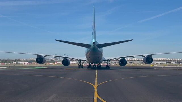 Immersive view from a jet cockpit taxiing behind a massive 747 jet taxinng slowly along madrid airport taxiways, with the terminal 4 and Madrid skyline at the background