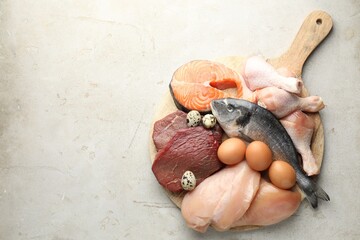 Naklejka premium Different types of fresh raw meat, fish and eggs on gray textured table, top view. Space for text