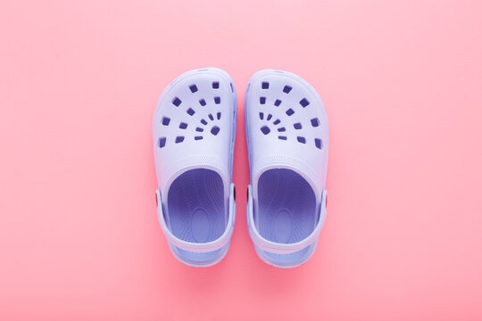 New purple foam slippers for little child girl on light pink table background. Pastel color. Closeup. Female summer footwear. Top down view.