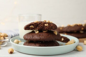Fototapeta premium Tasty chocolate cookies with hazelnuts and milk on white table, closeup