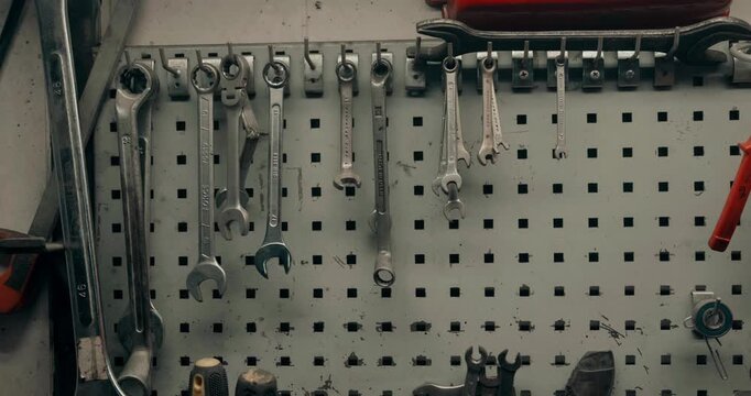 Someone taking a spanner from the tools hanging on the wall in a workshop