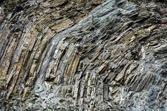 A detailed close-up view of layered rock formations in the Alps, showcasing natural geological structures, textures, and stratification shaped over millions of years in a mountainous environment.