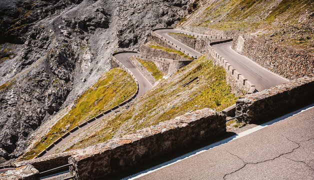 A scenic alpine road with dramatic hairpin curves winding through the mountains of the Stelvio Pass in South Tyrol.