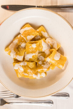 Gourmet presentation of traditional Italian paccheri pasta coated in a rich, creamy cheese sauce. The image highlights the large, tube-shaped pasta perfectly cooked and smothered in a velvety melted c